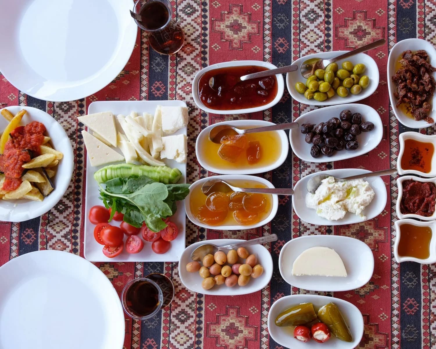Kilim örtü üzerinde beyaz peynir, kaşar, bal, reçel, zeytin ve domatesle kurulmuş kahvaltı sofrası